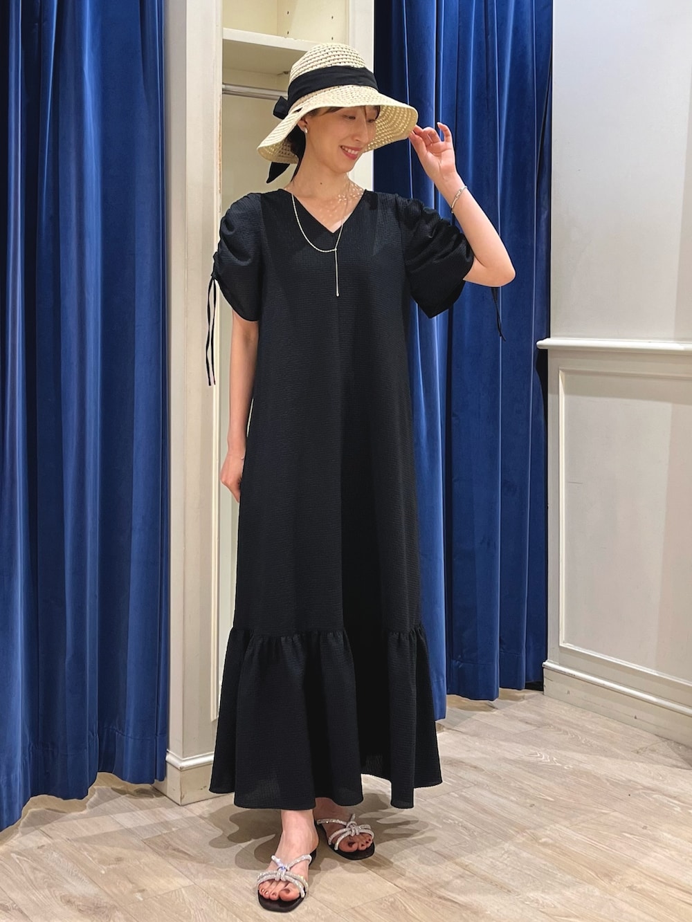 シルバー系のサンダル、ブラック系のワンピース、ベージュ系のハットを着用したレディースの春コーディネートの2枚目の写真