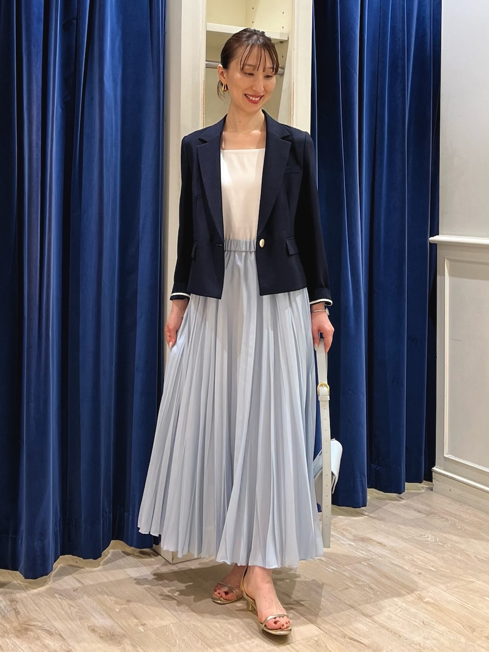 ブルー系のテーラードジャケット、ホワイト系のタンクトップ、ブルー系のスカートを着用したレディースの夏コーディネートの2枚目の写真
