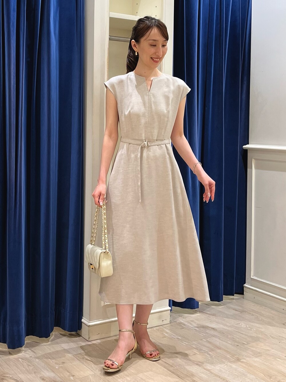 ベージュ系のワンピース、ホワイト系のショルダーバッグ、ゴールド系のサンダルを着用したレディースの夏コーディネートの9枚目の写真