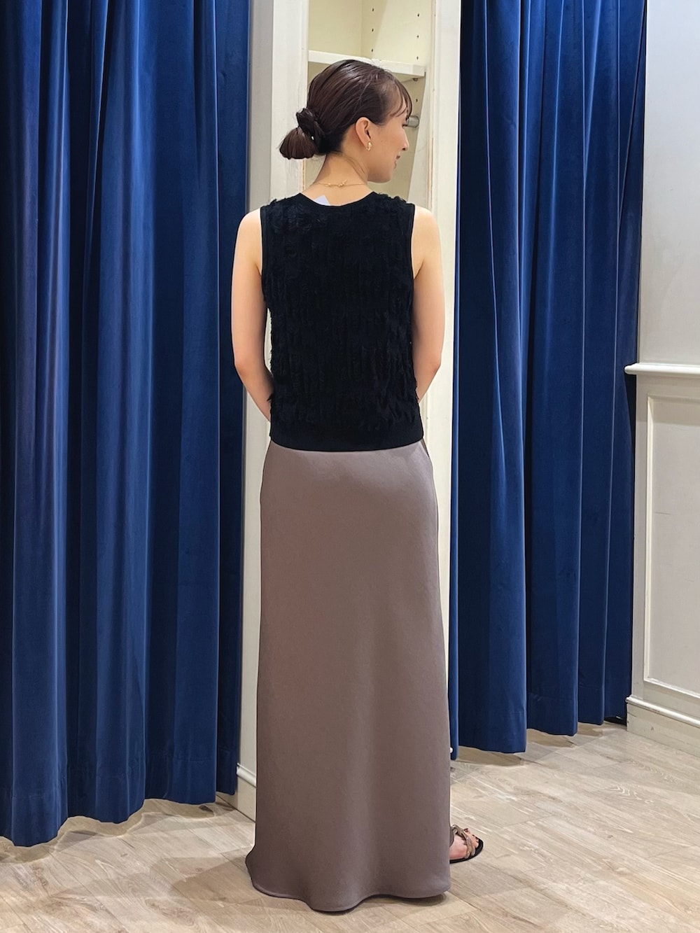 ブラック系のニット/セーター、グリーン系のスカート、ブラック系のかごバッグを着用したレディースの春コーディネートの9枚目の写真