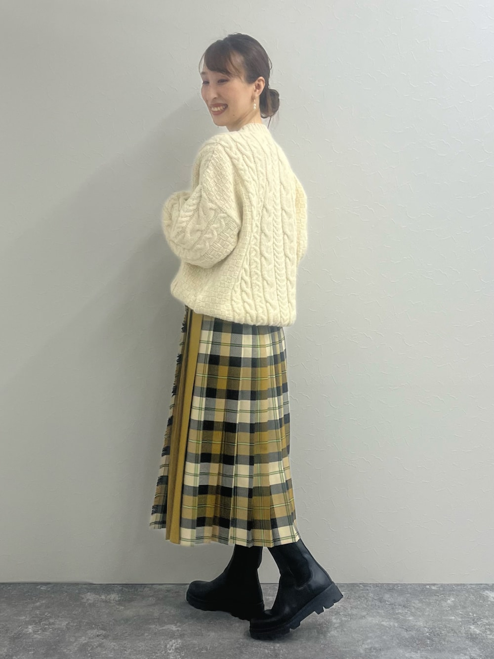 ホワイト系のニット/セーター、ベージュ系のスカート、ブラック系のブーツを着用したレディースの冬コーディネートの2枚目の写真