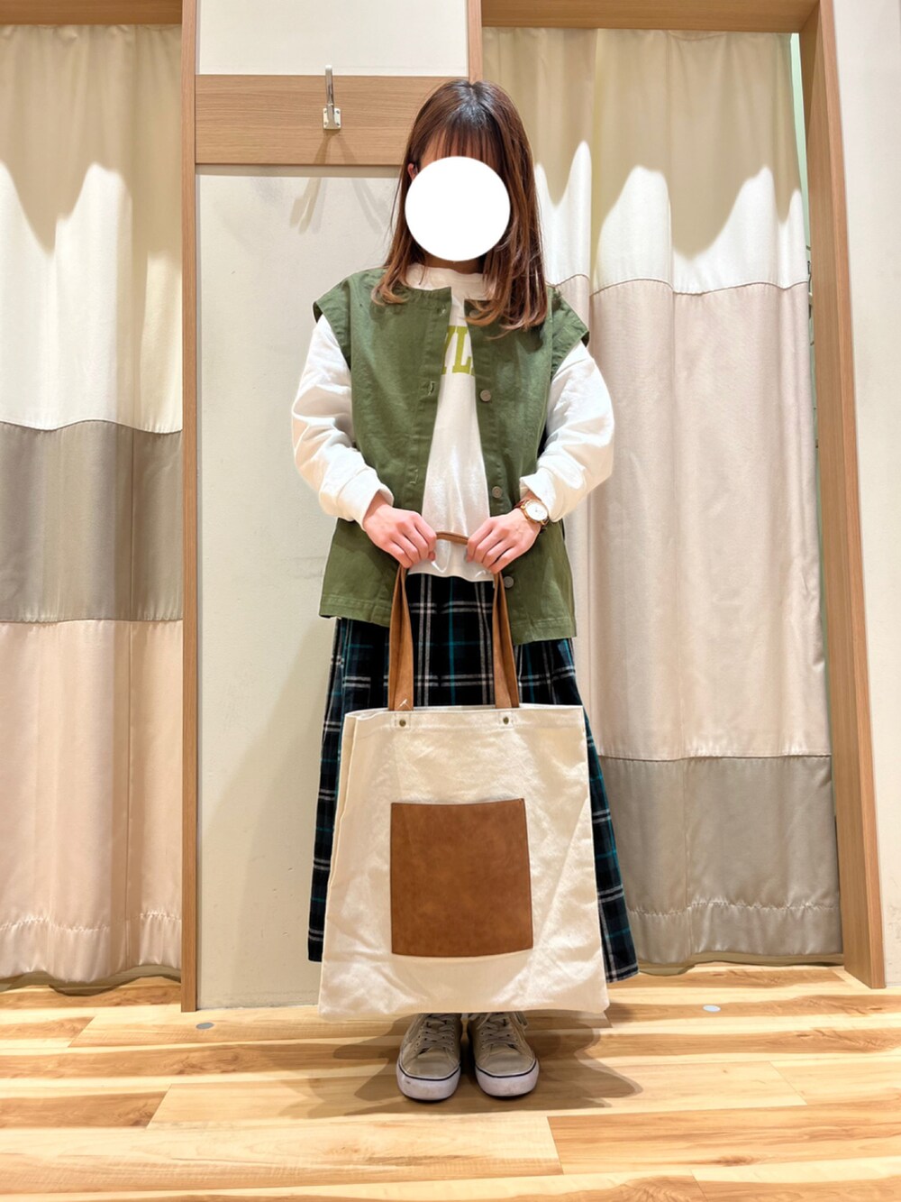 ブルー系のスカート、グリーン系のベスト、ホワイト系のTシャツ/カットソーを着用したレディースの春コーディネートの2枚目の写真