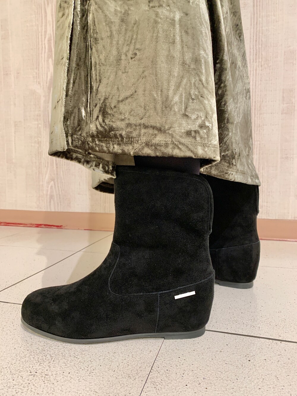 ブラック系のニット/セーター、グリーン系のスカート、ブラック系のブーツを着用したレディースの秋コーディネートの4枚目の写真