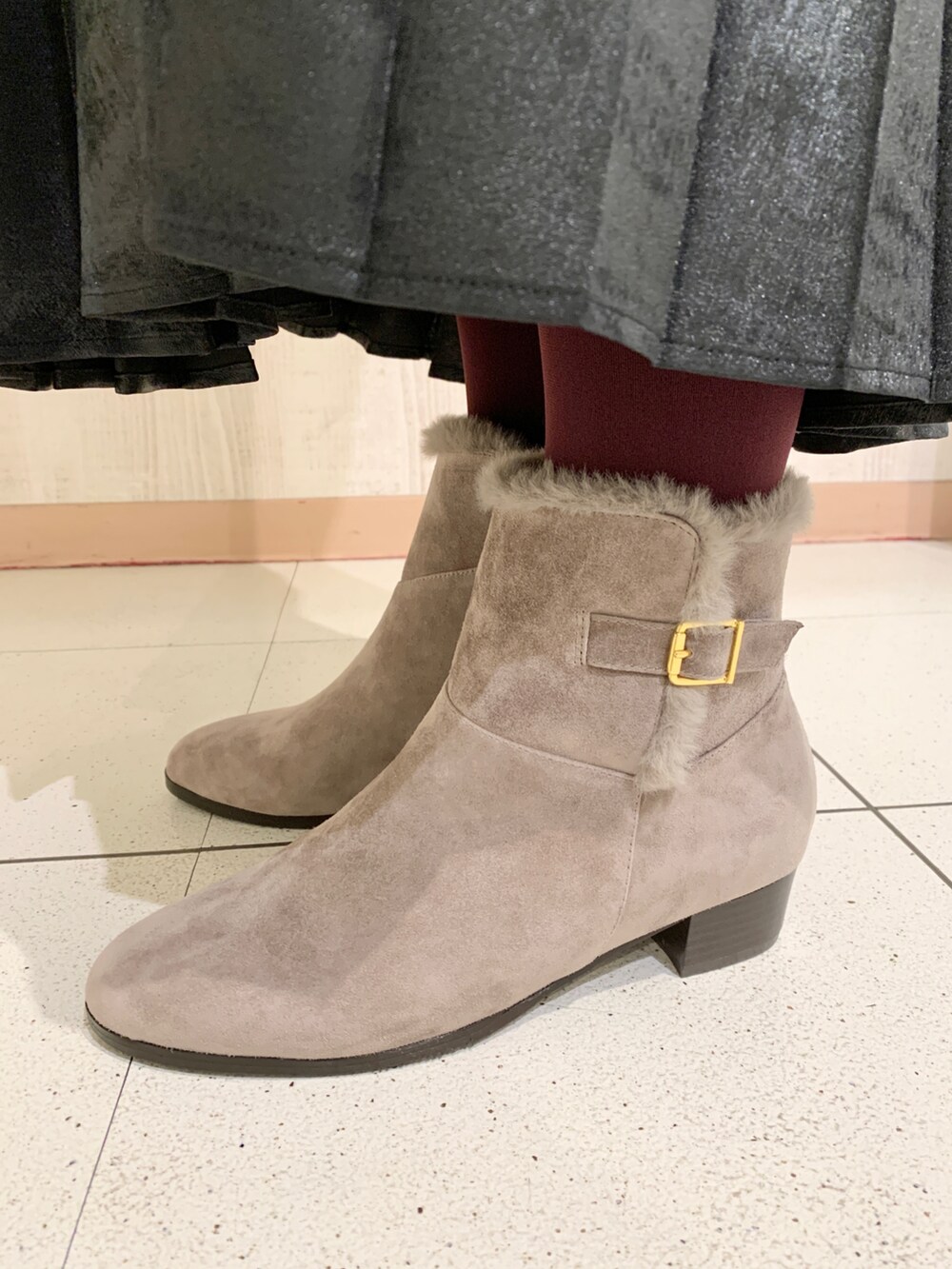 ブラック系のスカート、ベージュ系のブーツ、グレー系のブルゾンを着用したレディースの冬コーディネートの3枚目の写真