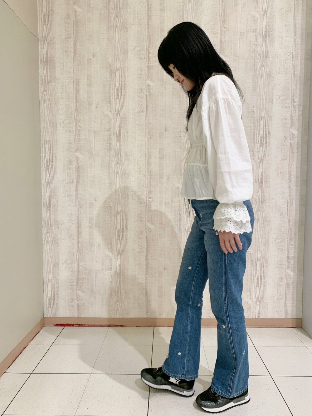 ブラック系のスニーカー、ホワイト系のシャツ/ブラウス、ブルー系のデニムパンツを着用したレディースの春コーディネートの2枚目の写真