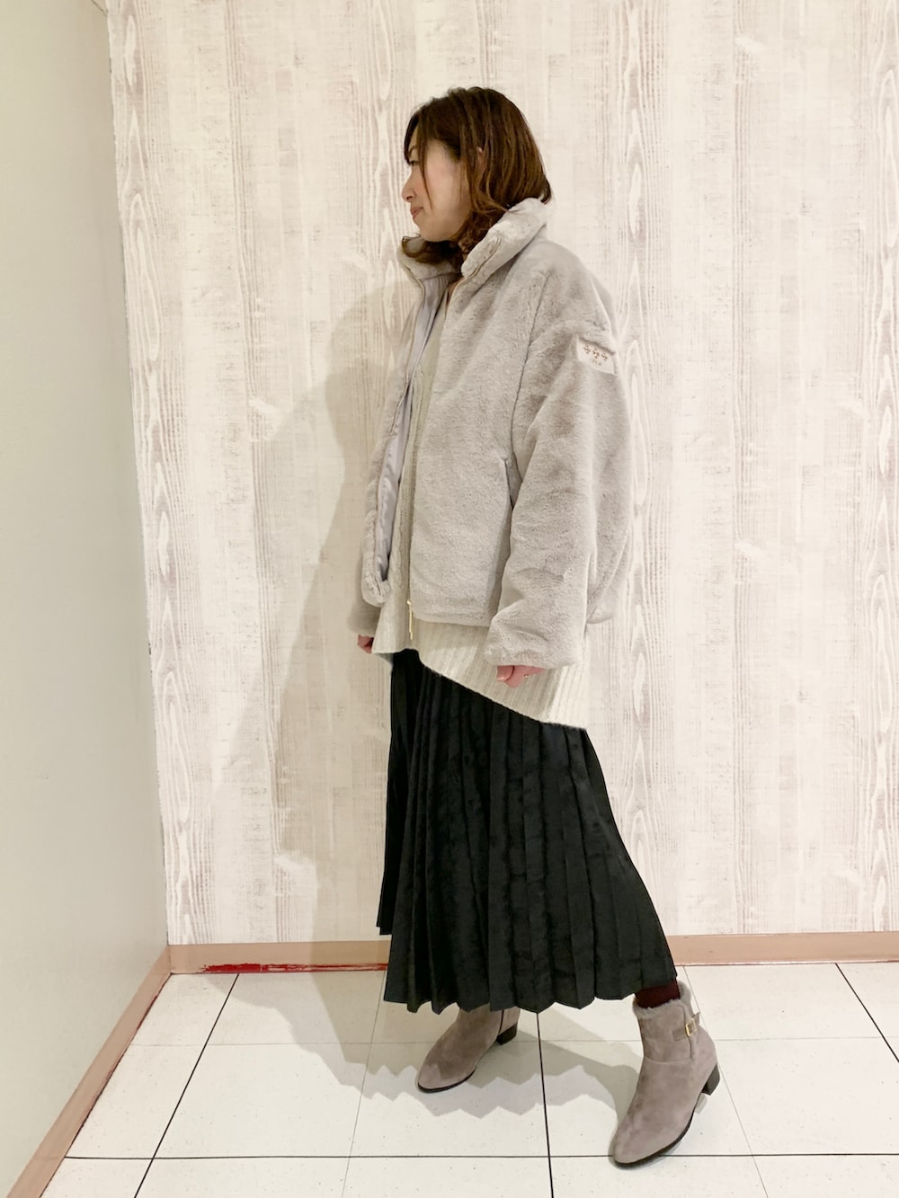 ブラック系のスカート、ベージュ系のブーツ、グレー系のブルゾンを着用したレディースの冬コーディネートの2枚目の写真