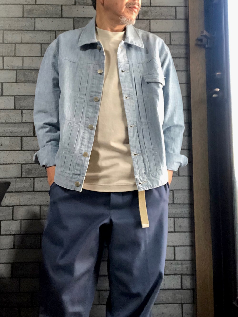 ブルー系のデニムジャケット、ベージュ系のTシャツ/カットソー、ブルー系のパンツを着用したメンズの春コーディネートの2枚目の写真