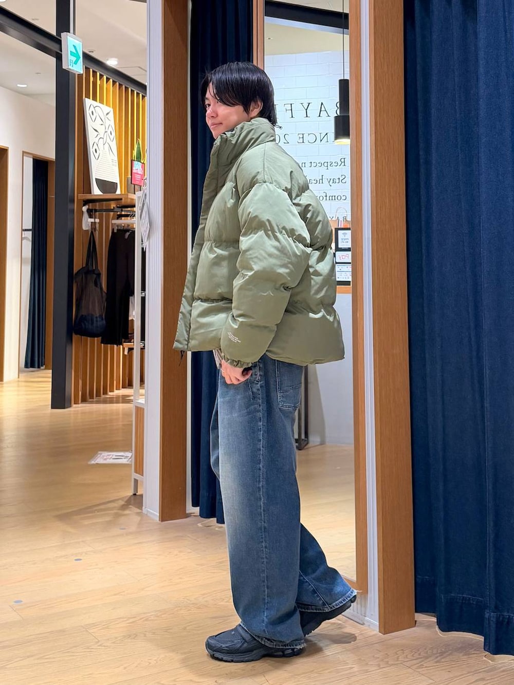 グリーン系のブルゾン、グレー系のショルダーバッグ、ブルー系のデニムパンツを着用したメンズの冬コーディネートの4枚目の写真