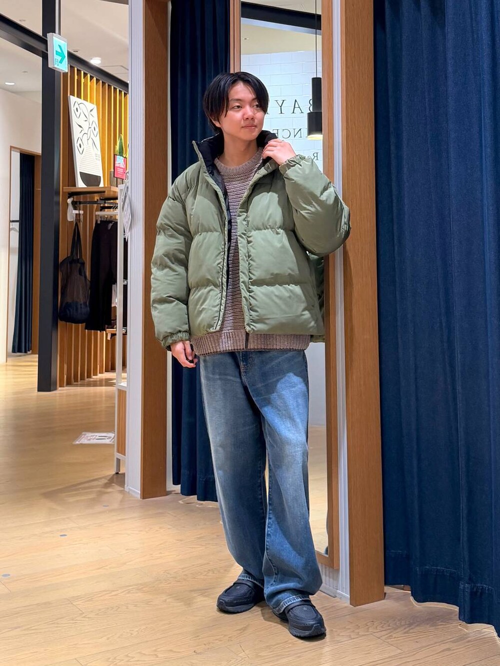 グリーン系のブルゾン、グレー系のショルダーバッグ、ブルー系のデニムパンツを着用したメンズの冬コーディネートの3枚目の写真