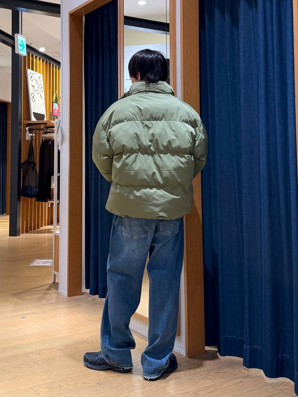 グリーン系のブルゾン、グレー系のショルダーバッグ、ブルー系のデニムパンツを着用したメンズの冬コーディネートの5枚目の写真