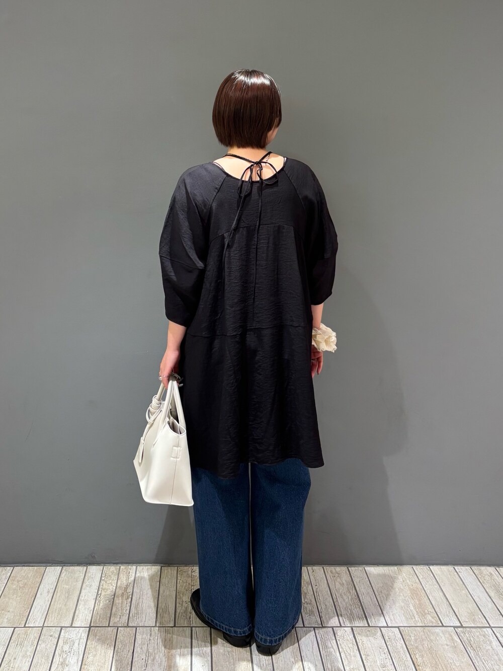 ブラック系のワンピース、ホワイト系のハンドバッグ、ブルー系のデニムパンツを着用したレディースの春コーディネートの4枚目の写真