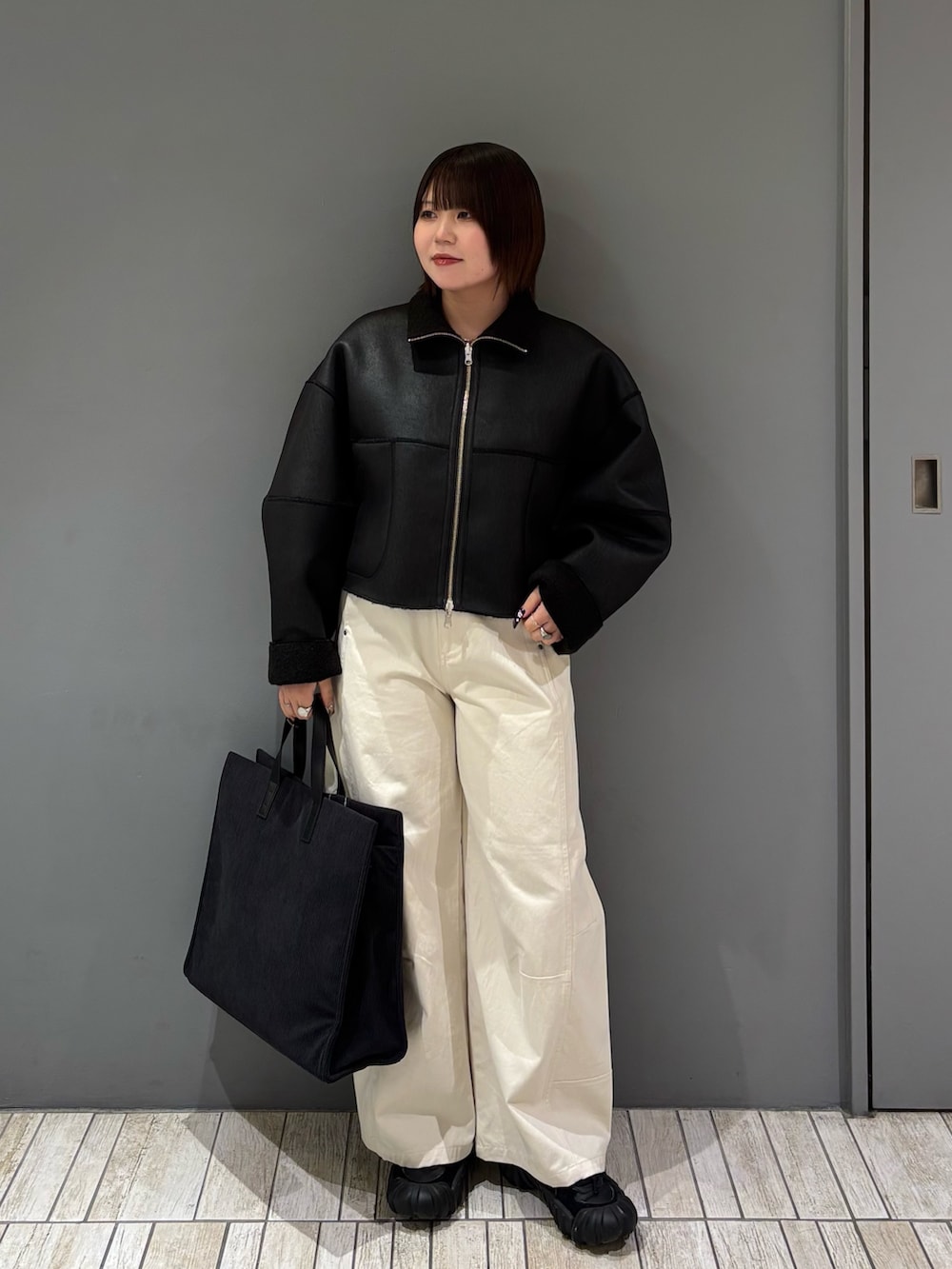 ブラック系のその他アウター、ホワイト系のその他パンツ、グレー系のトートバッグを着用したレディースの冬コーディネートの3枚目の写真