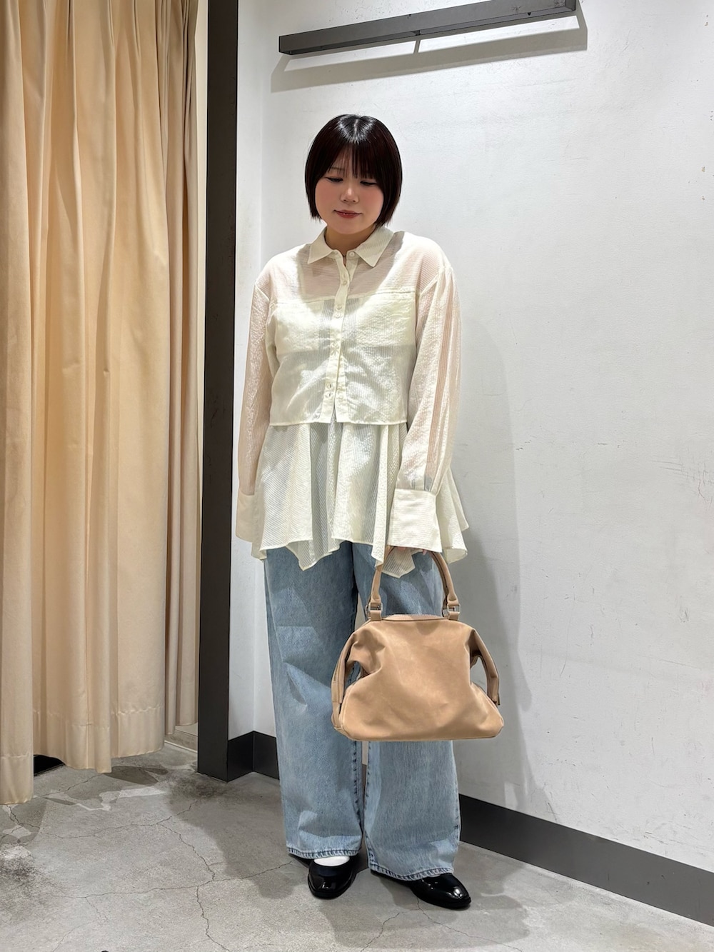 ベージュ系のボストンバッグ、ホワイト系のシャツ/ブラウス、ブルー系のデニムパンツを着用したレディースの春コーディネートの3枚目の写真