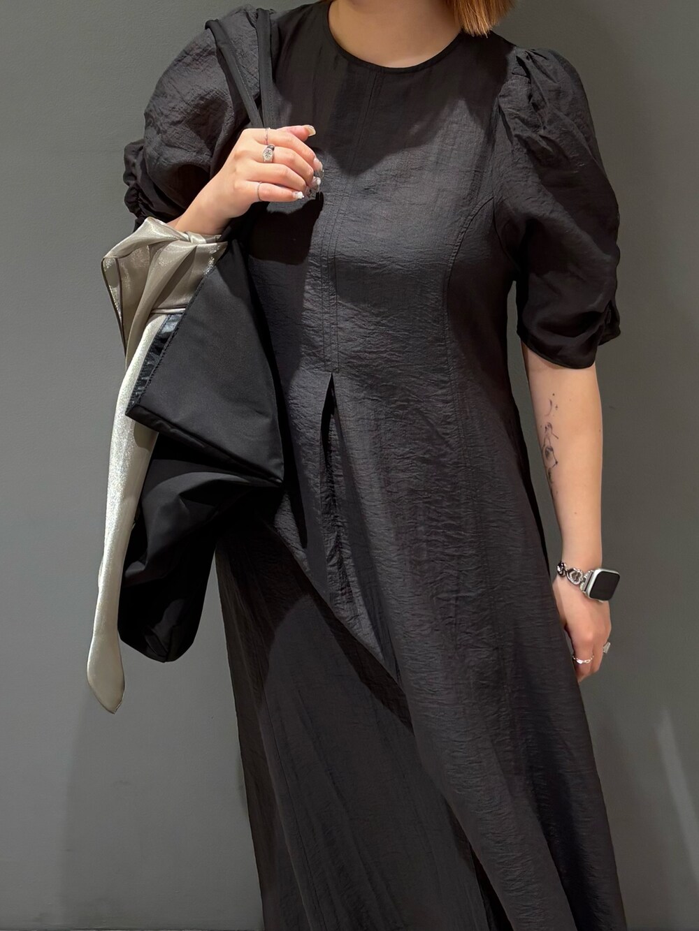ブラック系のショルダーバッグ、ブルー系のデニムパンツ、グレー系のワンピースを着用したレディースの春コーディネートの8枚目の写真