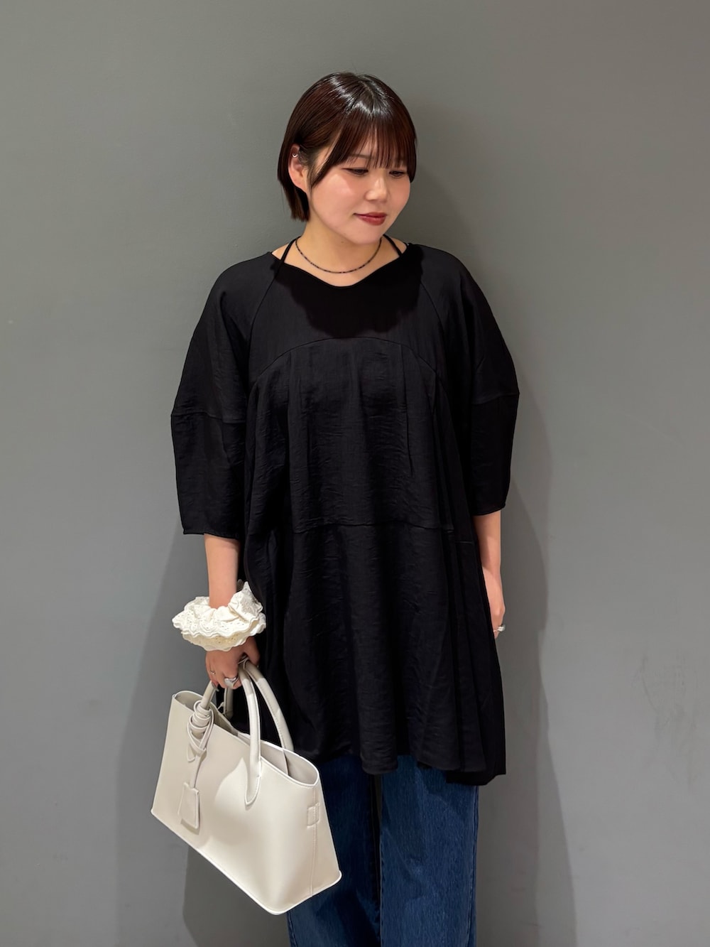 ブラック系のワンピース、ホワイト系のハンドバッグ、ブルー系のデニムパンツを着用したレディースの春コーディネートの5枚目の写真