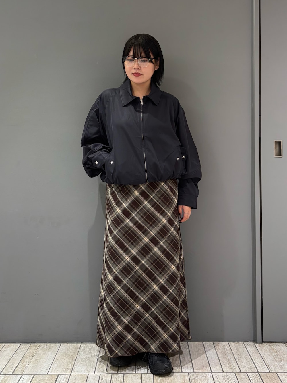 ブルー系のブルゾン、ブラウン系のスカート、ブラック系のメガネを着用したレディースの秋コーディネートの2枚目の写真