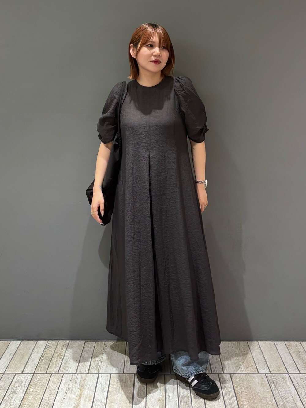 ブラック系のショルダーバッグ、ブルー系のデニムパンツ、グレー系のワンピースを着用したレディースの春コーディネートの6枚目の写真