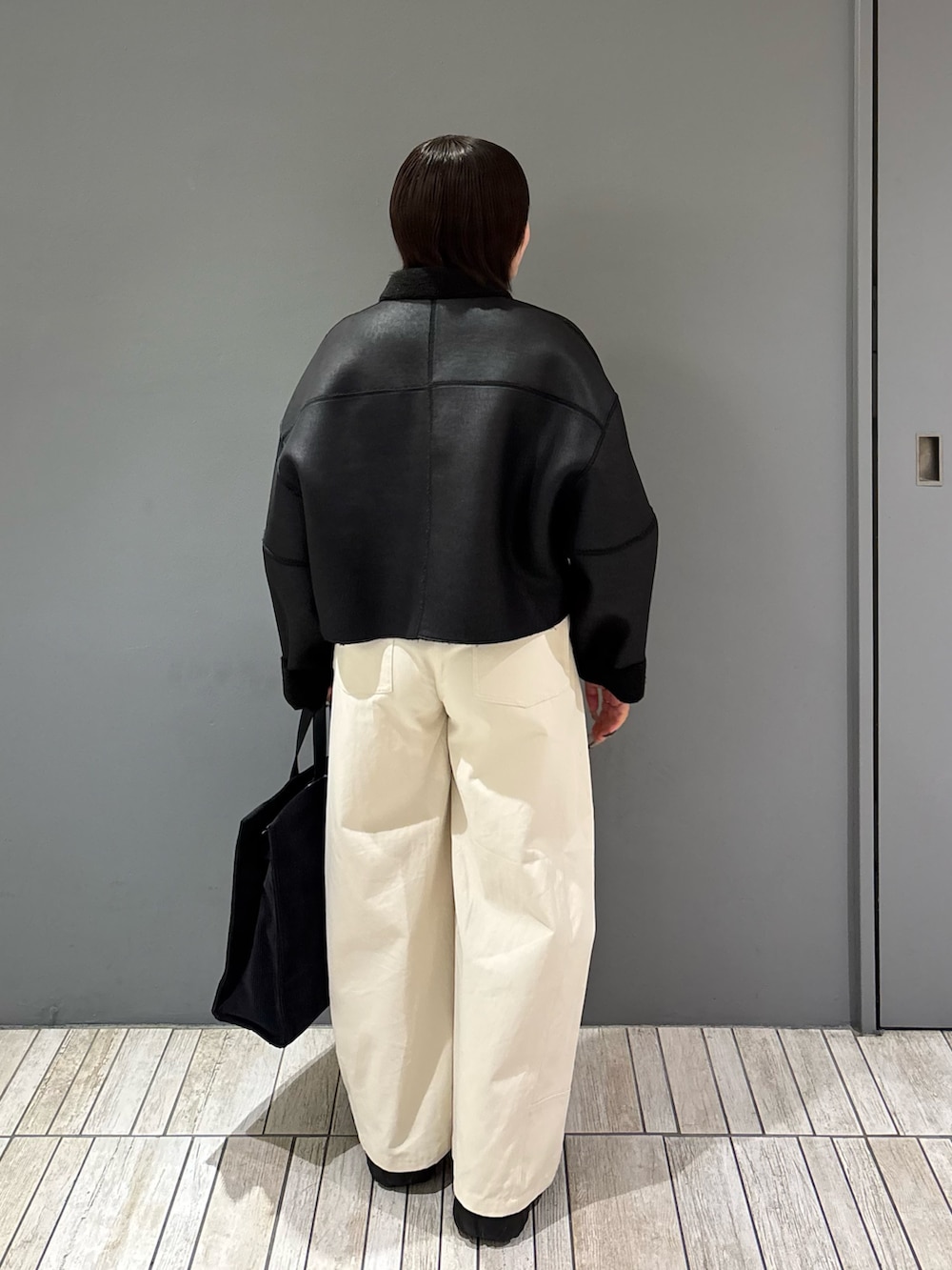 ブラック系のその他アウター、ホワイト系のその他パンツ、グレー系のトートバッグを着用したレディースの冬コーディネートの5枚目の写真