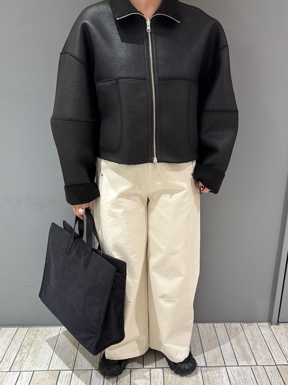 ブラック系のその他アウター、ホワイト系のその他パンツ、グレー系のトートバッグを着用したレディースの冬コーディネートの7枚目の写真