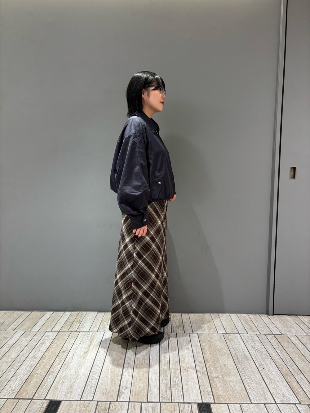 ブルー系のブルゾン、ブラウン系のスカート、ブラック系のメガネを着用したレディースの秋コーディネートの7枚目の写真