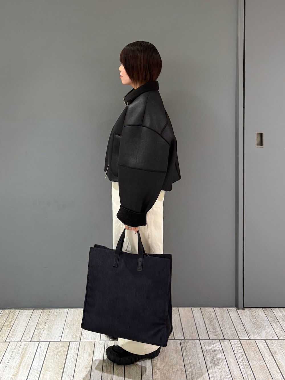 ブラック系のその他アウター、ホワイト系のその他パンツ、グレー系のトートバッグを着用したレディースの冬コーディネートの4枚目の写真