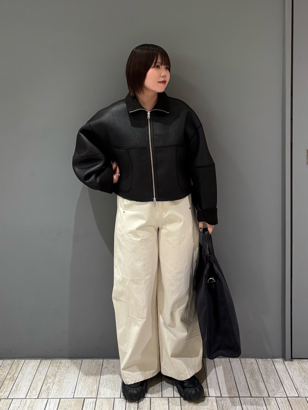 ブラック系のその他アウター、ホワイト系のその他パンツ、グレー系のトートバッグを着用したレディースの冬コーディネートの2枚目の写真