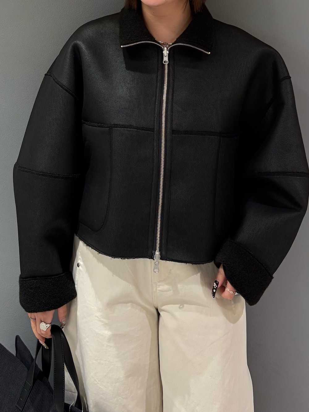 ブラック系のその他アウター、ホワイト系のその他パンツ、グレー系のトートバッグを着用したレディースの冬コーディネートの6枚目の写真