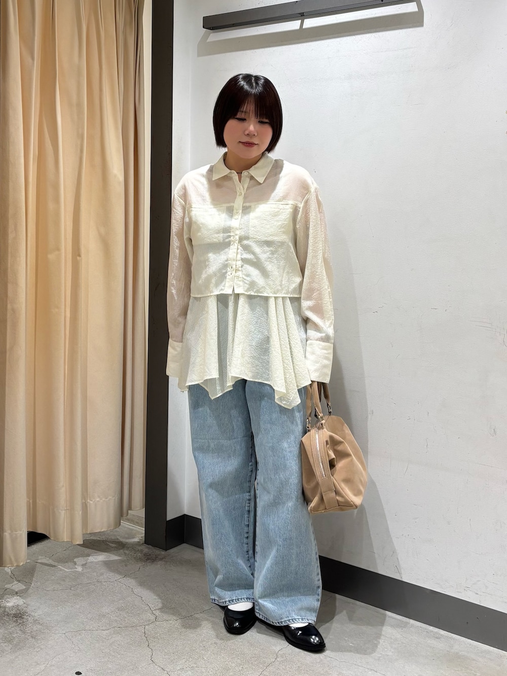 ベージュ系のボストンバッグ、ホワイト系のシャツ/ブラウス、ブルー系のデニムパンツを着用したレディースの春コーディネートの2枚目の写真