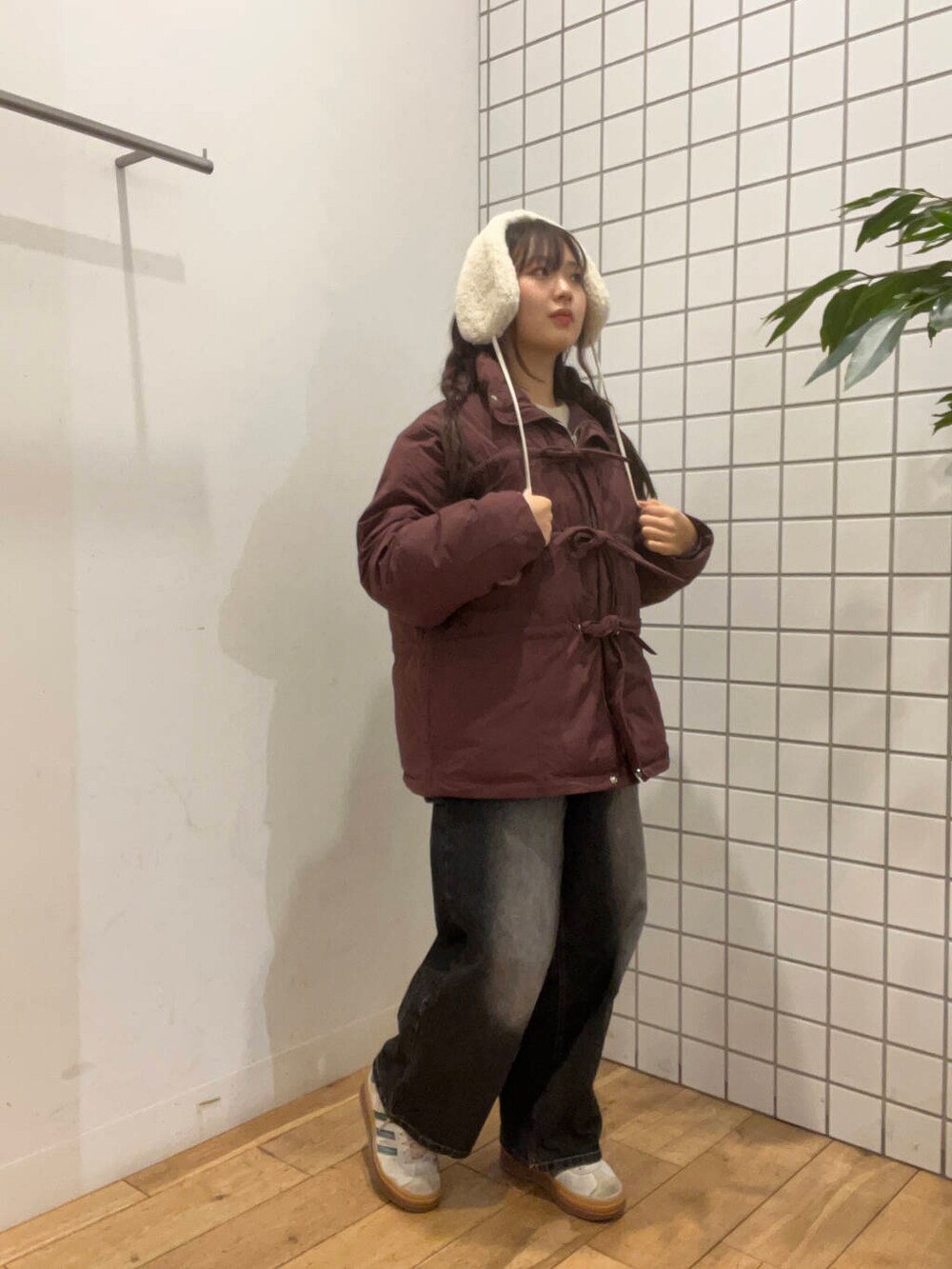 レッド系のダウンジャケット/コート、ブラック系のデニムパンツ、ベージュ系のニット/セーターを着用したレディースの冬コーディネートの2枚目の写真