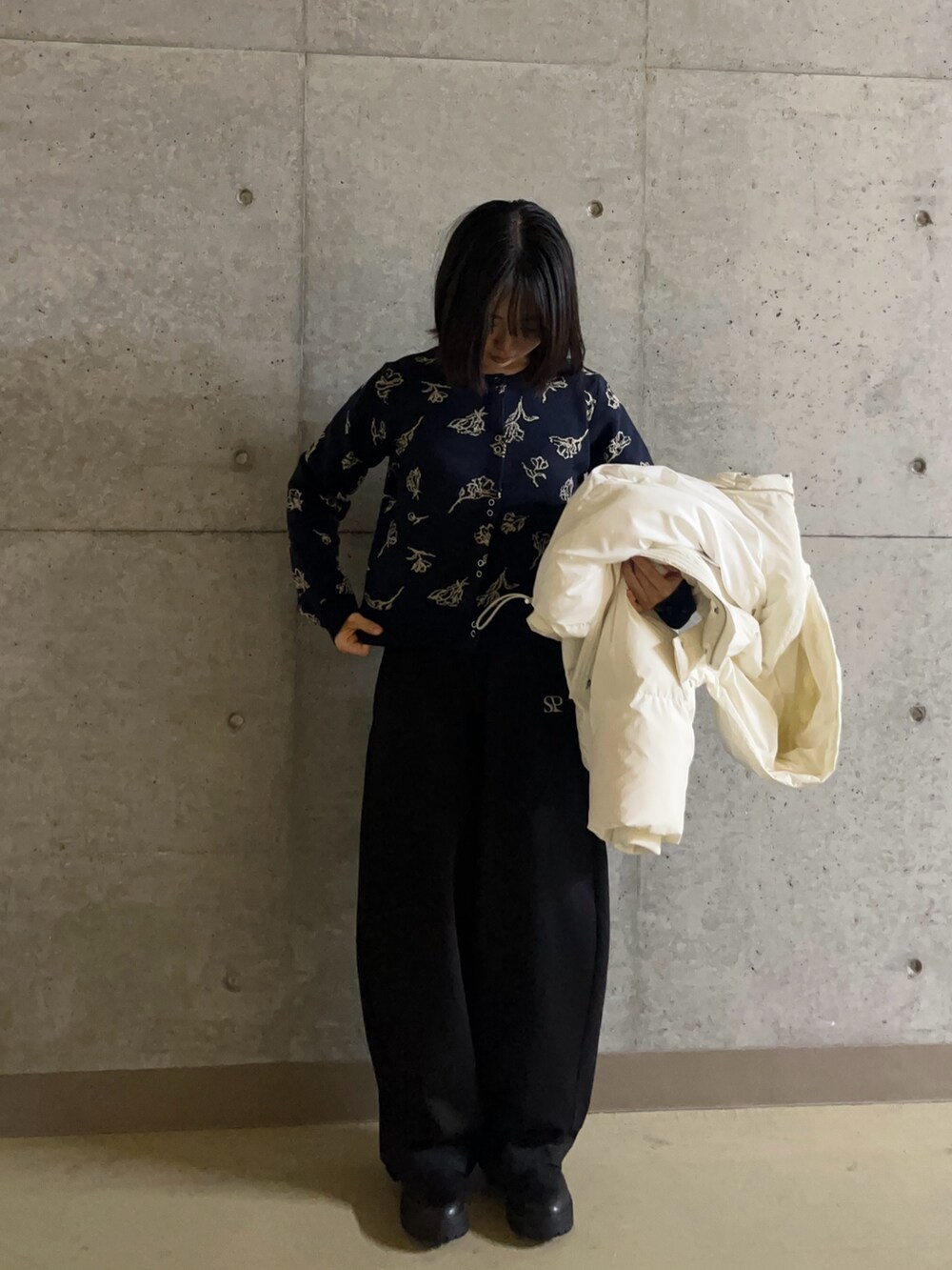 ホワイト系のダウンジャケット/コート、ブラック系のその他パンツ、ブルー系のカーディガン/ボレロを着用したレディースの秋コーディネートの2枚目の写真