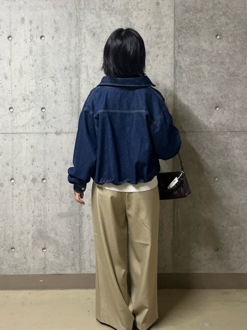 ブルー系のデニムジャケット、ホワイト系のニット/セーター、ベージュ系のその他パンツを着用したレディースの秋コーディネートの3枚目の写真