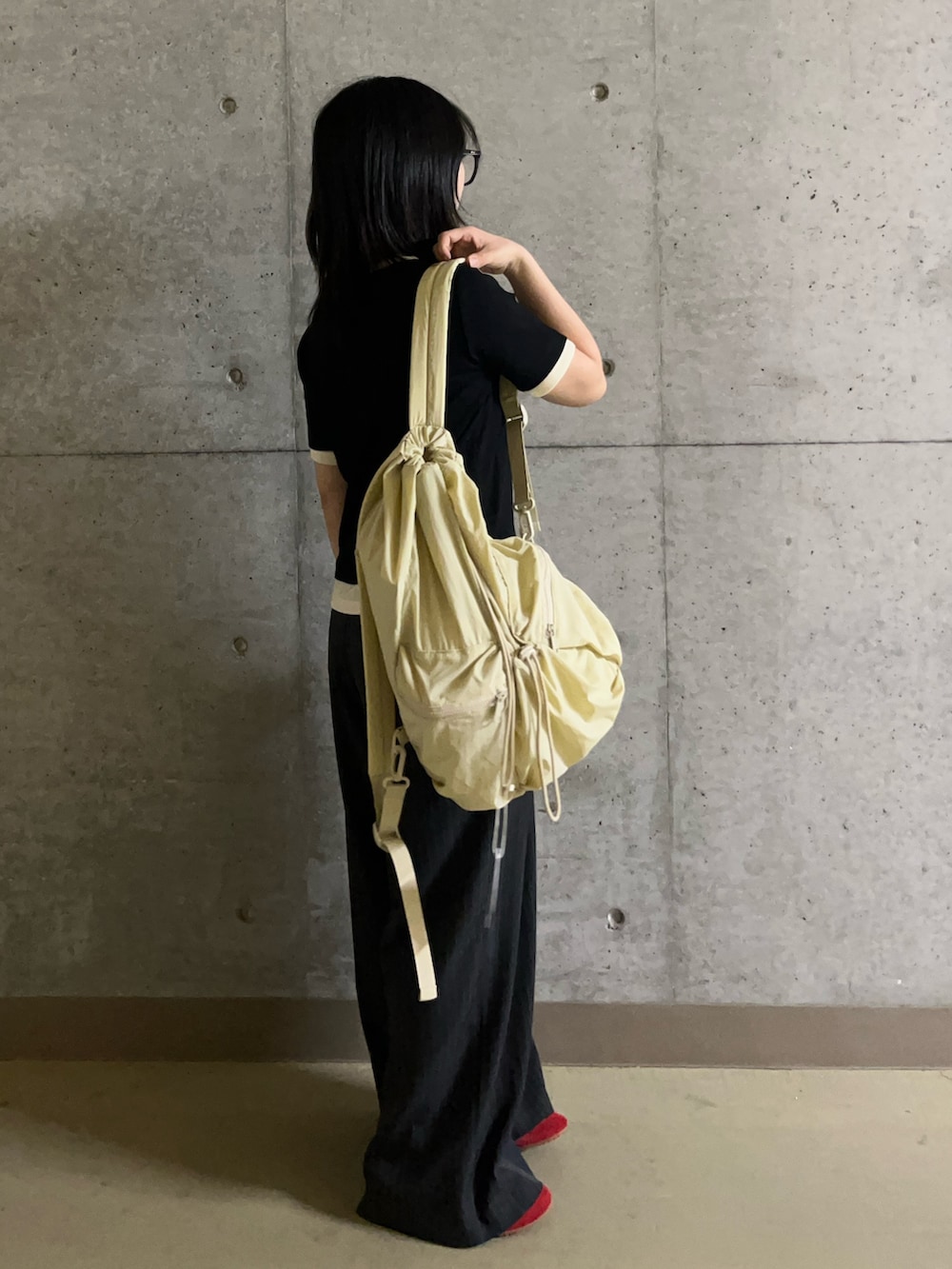ブラック系のTシャツ/カットソー、グレー系のスラックス、ベージュ系のバックパック/リュックを着用したレディースの夏コーディネートの2枚目の写真