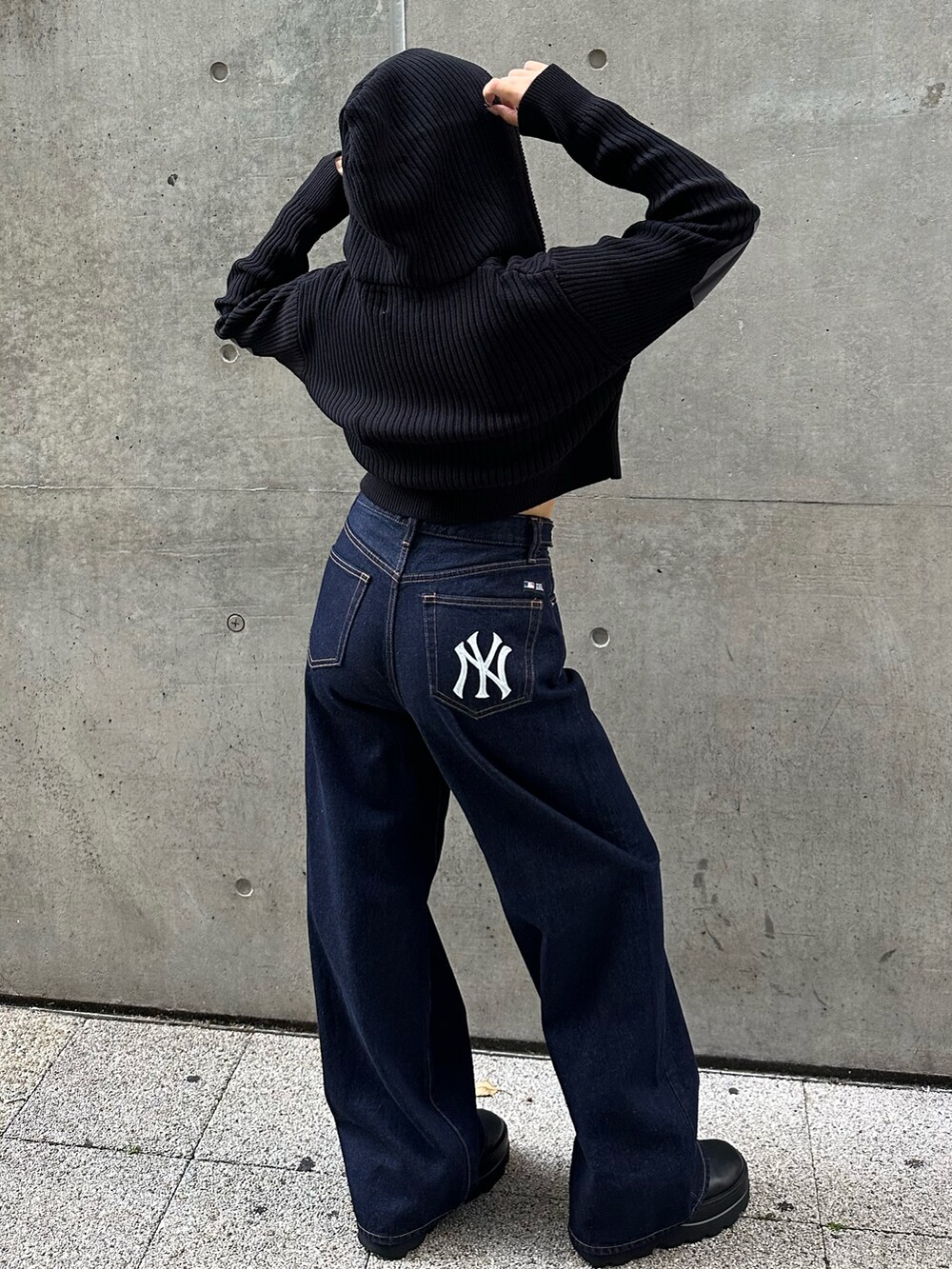 ブラック系のパーカー、ブラック系のデニムパンツ、ブラック系のブーツを着用したレディースの秋コーディネートの2枚目の写真