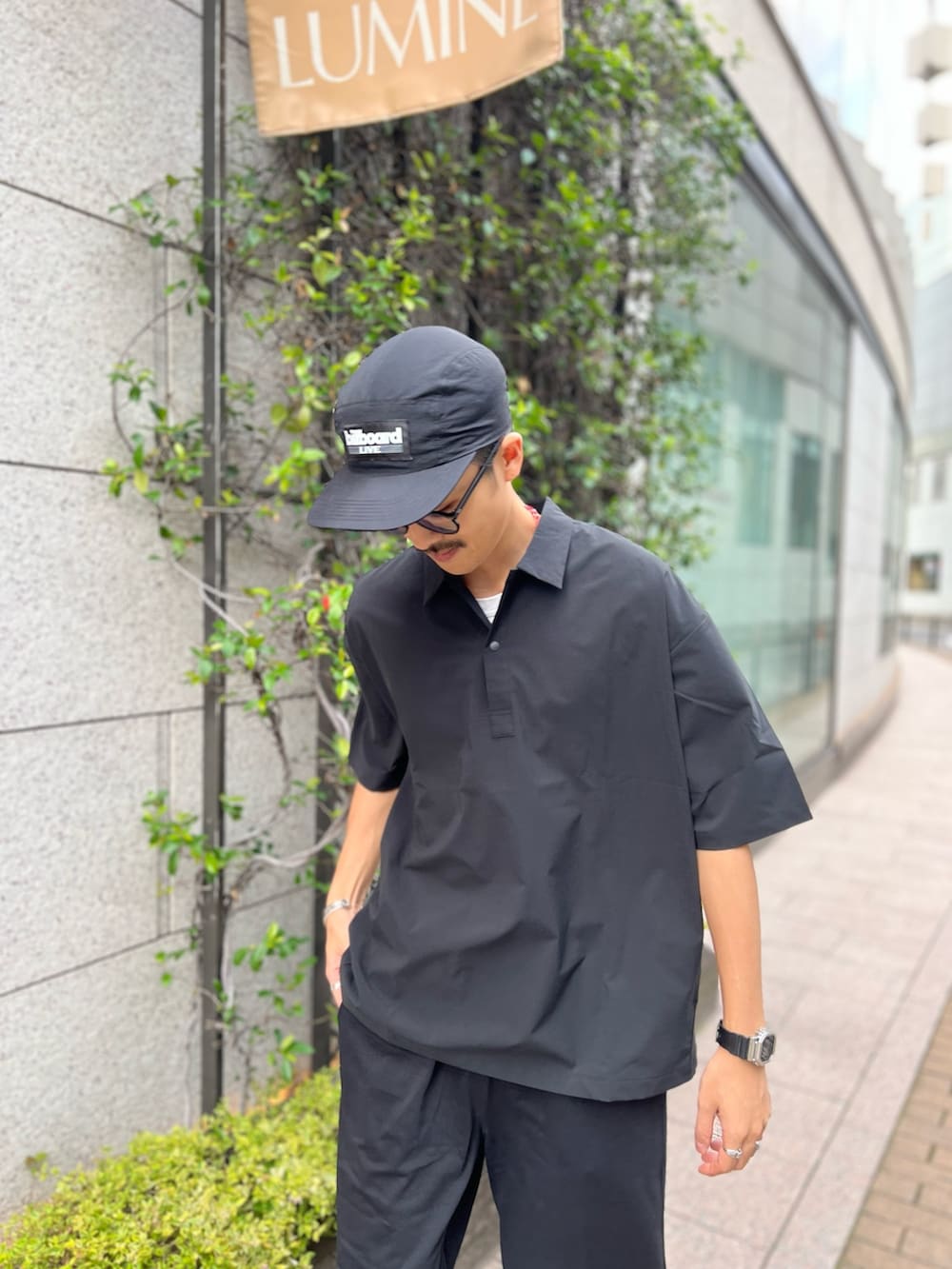 ブラック系のポロシャツ、ブラック系のその他パンツを着用したメンズの夏コーディネートの2枚目の写真