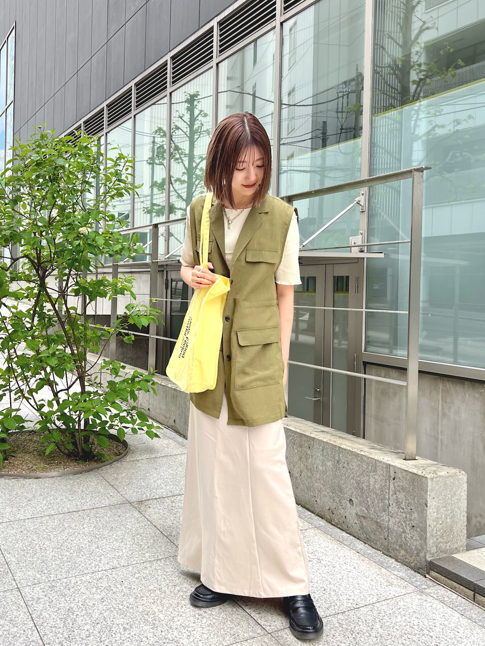 グリーン系のベスト、ホワイト系のTシャツ/カットソー、ホワイト系のワンピースを着用したレディースの春コーディネートの3枚目の写真
