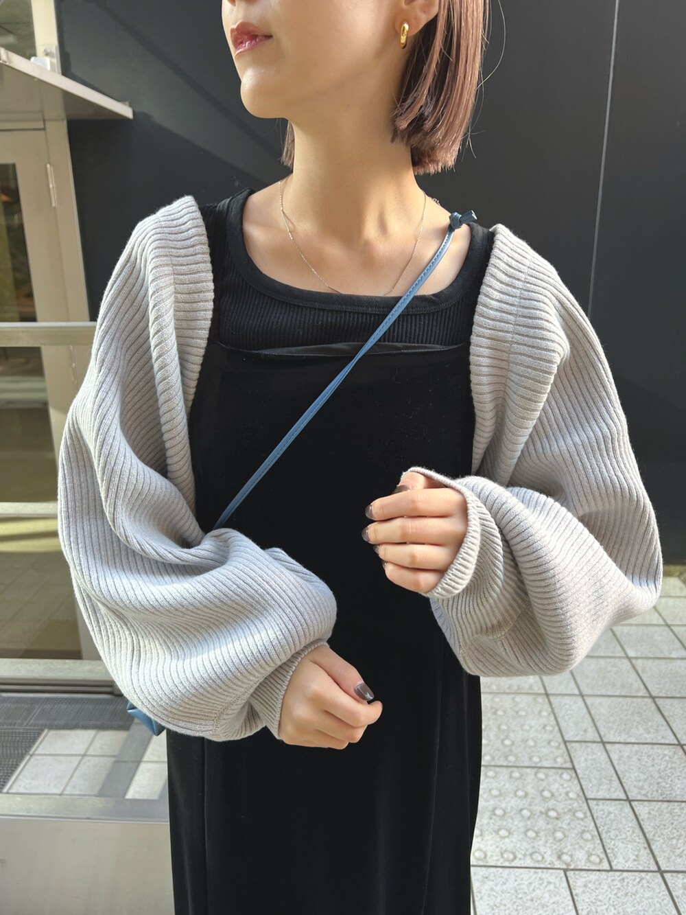 グレー系のカーディガン/ボレロ、ブラック系のワンピース、ブルー系のショルダーバッグを着用したレディースの秋コーディネートの3枚目の写真
