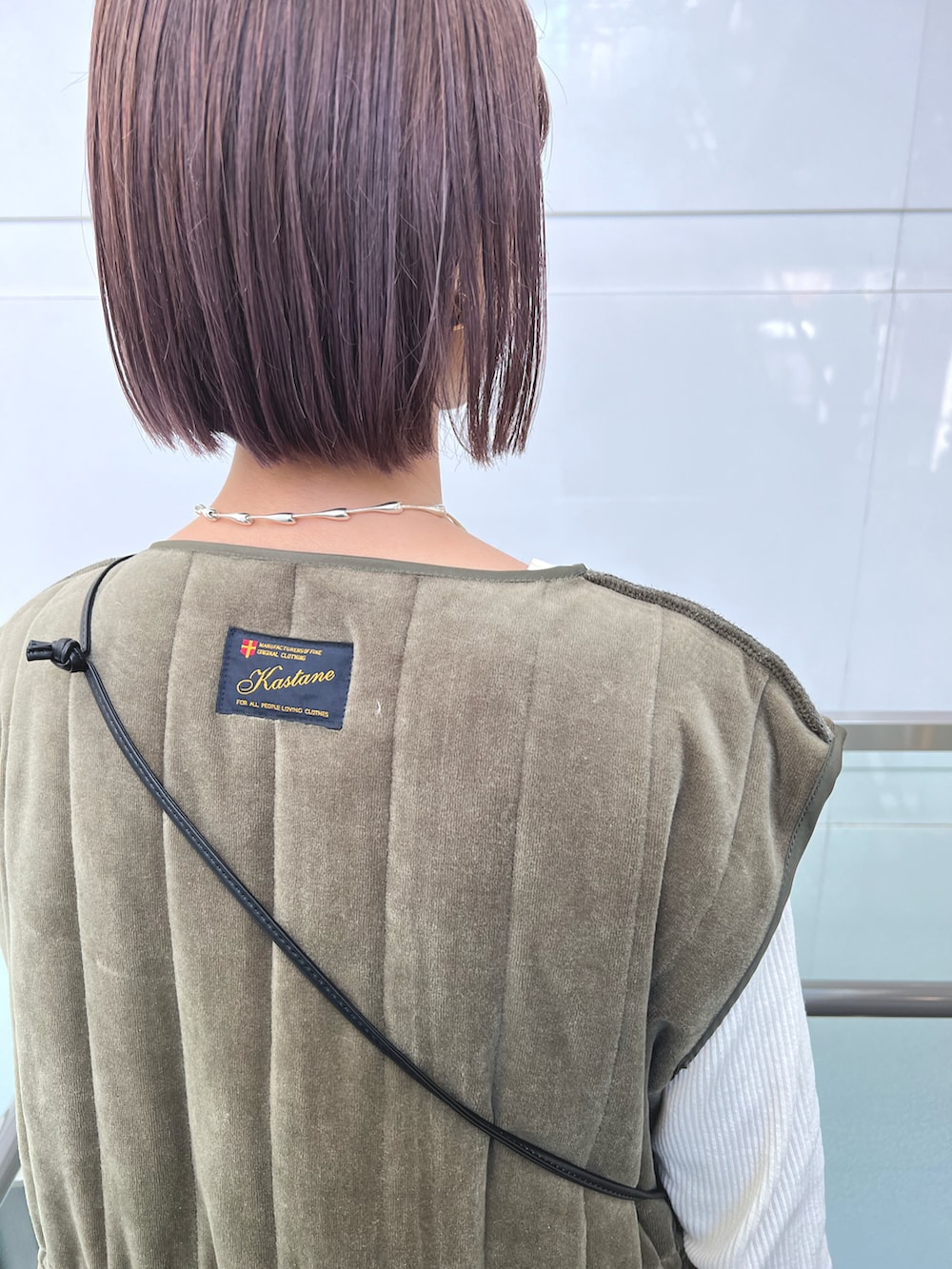 グリーン系のベスト、ブラック系のショルダーバッグ、ブラック系のワンピースを着用したレディースの秋コーディネートの3枚目の写真