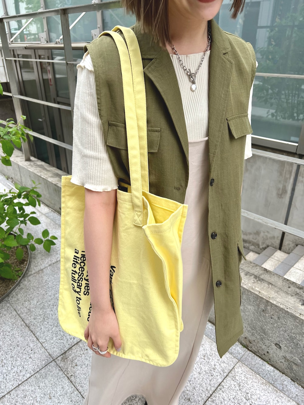 グリーン系のベスト、ホワイト系のTシャツ/カットソー、ホワイト系のワンピースを着用したレディースの春コーディネートの4枚目の写真