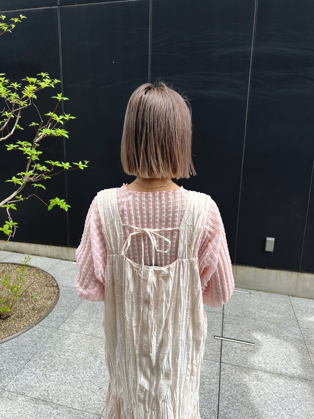 ピンク系のニット/セーター、ホワイト系のワンピースを着用したレディースの春コーディネートの3枚目の写真