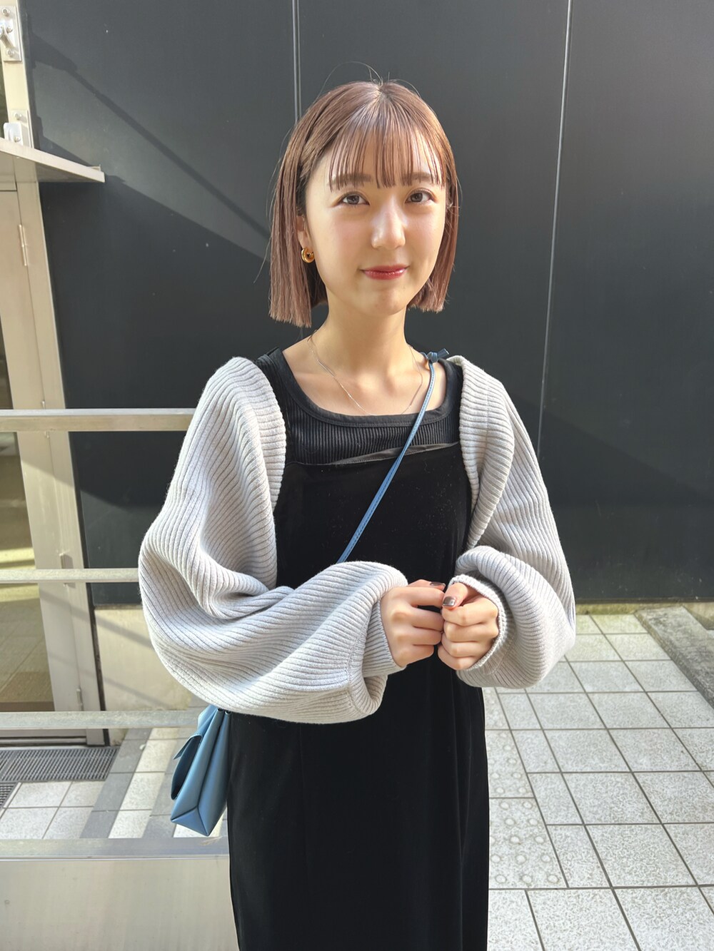 グレー系のカーディガン/ボレロ、ブラック系のワンピース、ブルー系のショルダーバッグを着用したレディースの秋コーディネートの2枚目の写真