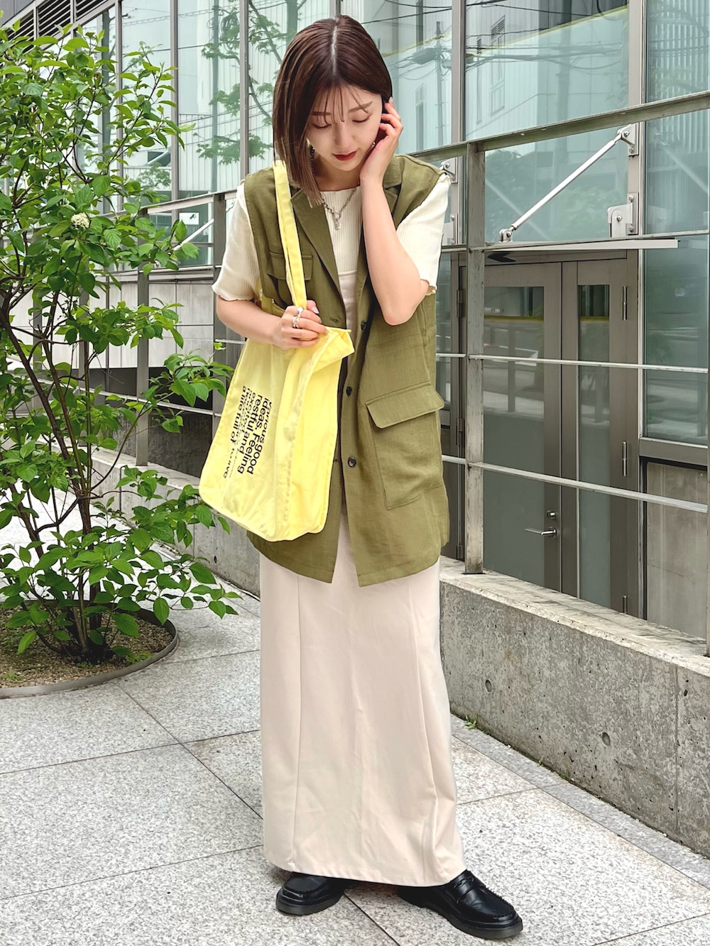 グリーン系のベスト、ホワイト系のTシャツ/カットソー、ホワイト系のワンピースを着用したレディースの春コーディネートの2枚目の写真