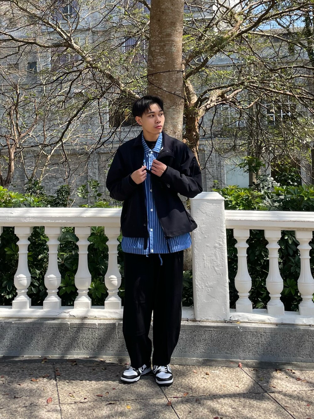 ブラック系のチノパンツ、ブラック系のスニーカー、ブラック系のブルゾンを着用したメンズの春コーディネートの2枚目の写真