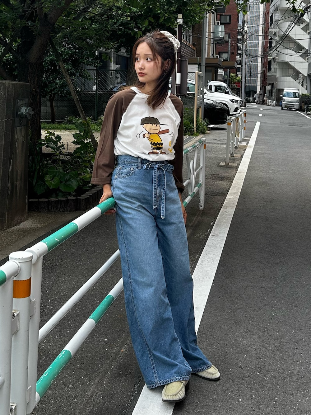 ブルー系のデニムパンツ、ベージュ系のローファー、ブラウン系のTシャツ/カットソーを着用したレディースの夏コーディネートの3枚目の写真