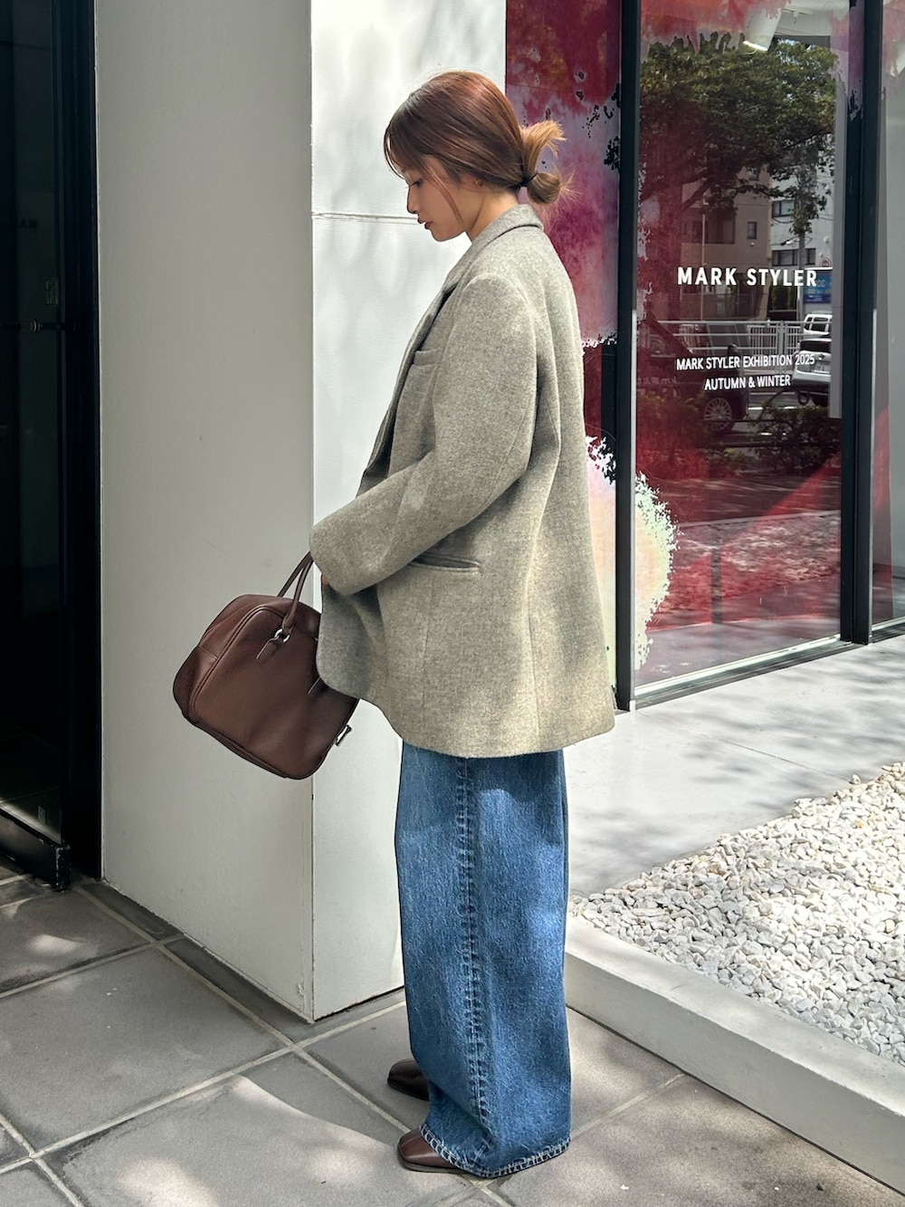 グレー系のテーラードジャケット、ホワイト系のニット/セーター、ブルー系のデニムパンツを着用したレディースの秋コーディネートの3枚目の写真