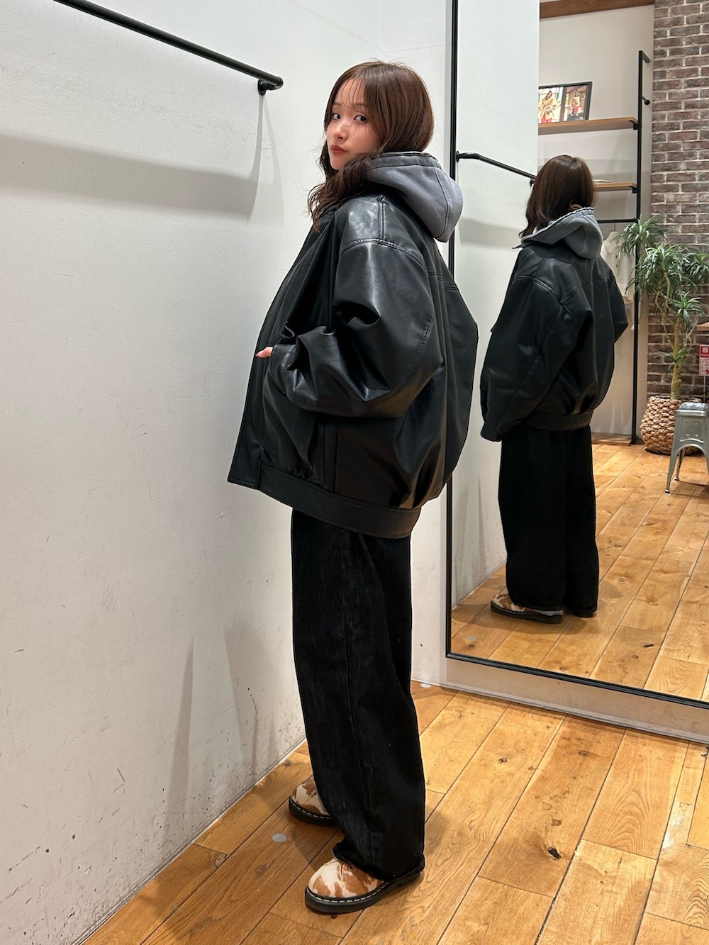 ブラック系のブルゾン、グレー系のパーカー、ブラック系のデニムパンツを着用したレディースの冬コーディネートの3枚目の写真