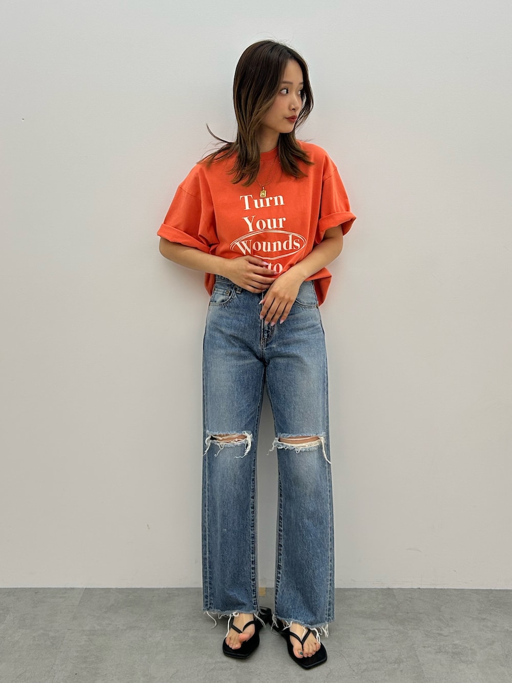 ブルー系のデニムパンツ、オレンジ系のTシャツ/カットソー、ブラック系のサンダルを着用したレディースの春コーディネートの3枚目の写真