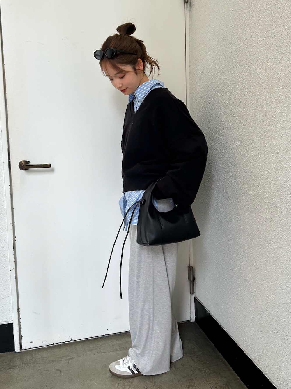 ブラック系のスウェット、ブルー系のシャツ/ブラウス、ブラック系のハンドバッグを着用したレディースの春コーディネートの3枚目の写真