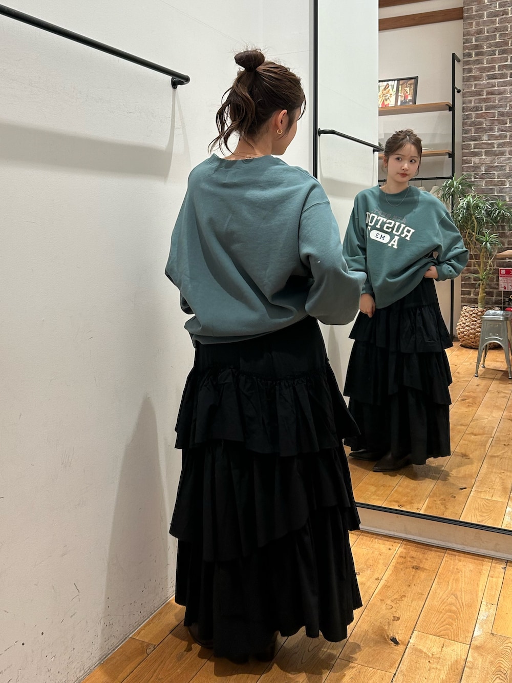 グリーン系のスウェット、ブラック系のスカートを着用したレディースの冬コーディネートの4枚目の写真