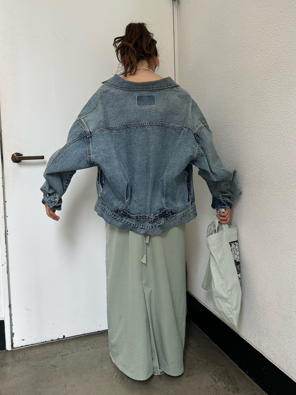 グリーン系のトートバッグ、ブルー系のスニーカー、ブルー系のデニムジャケットを着用したレディースの春コーディネートの4枚目の写真