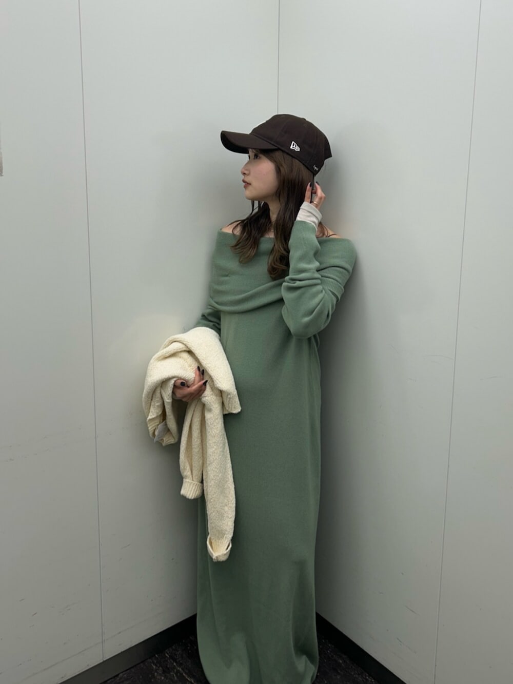 ブラック系のスリッポン、グリーン系のワンピース、ホワイト系のニット/セーターを着用したレディースの冬コーディネートの6枚目の写真